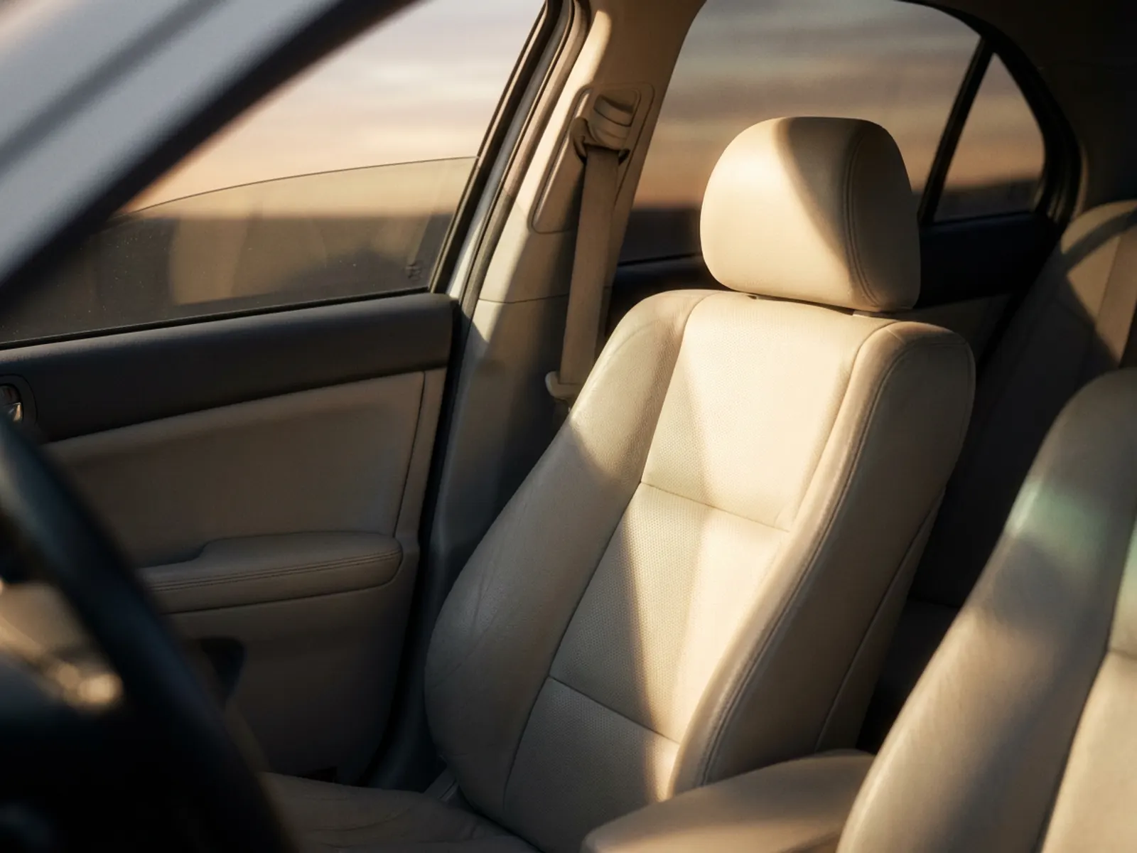 Late-afternoon sunlight through a parked car's side window falling across a pale leather seat